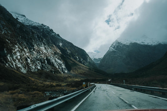 nz road going into a snowy cold mountain range