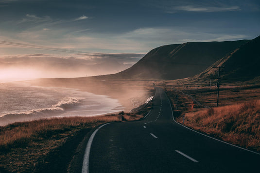 misty coastal road, winding along the ocean, dry long grass, blue skies