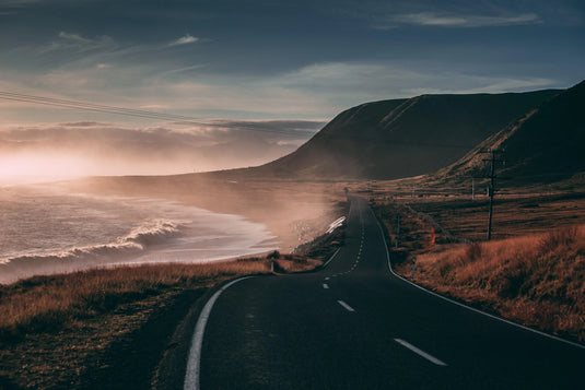 misty coastal road, winding along the ocean, dry long grass, blue skies