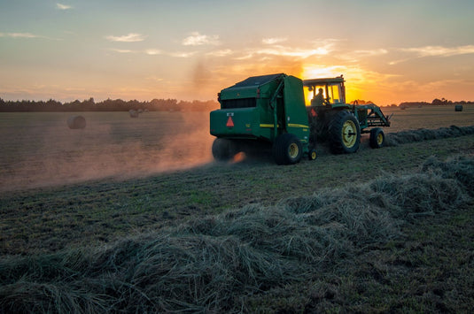 John Deere tractor working at sunset harvesting a farm paddock