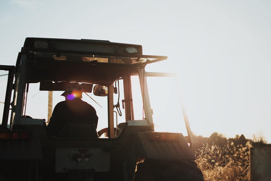 Blue skies with a silhouette of tractor with man driving