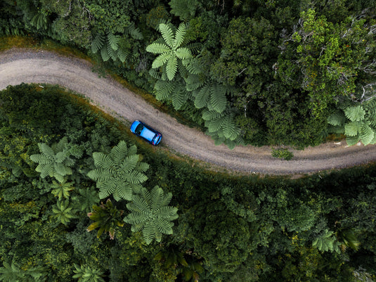 aerial image of typical nz bush, gravel road, outdoor adventures, car driving along road